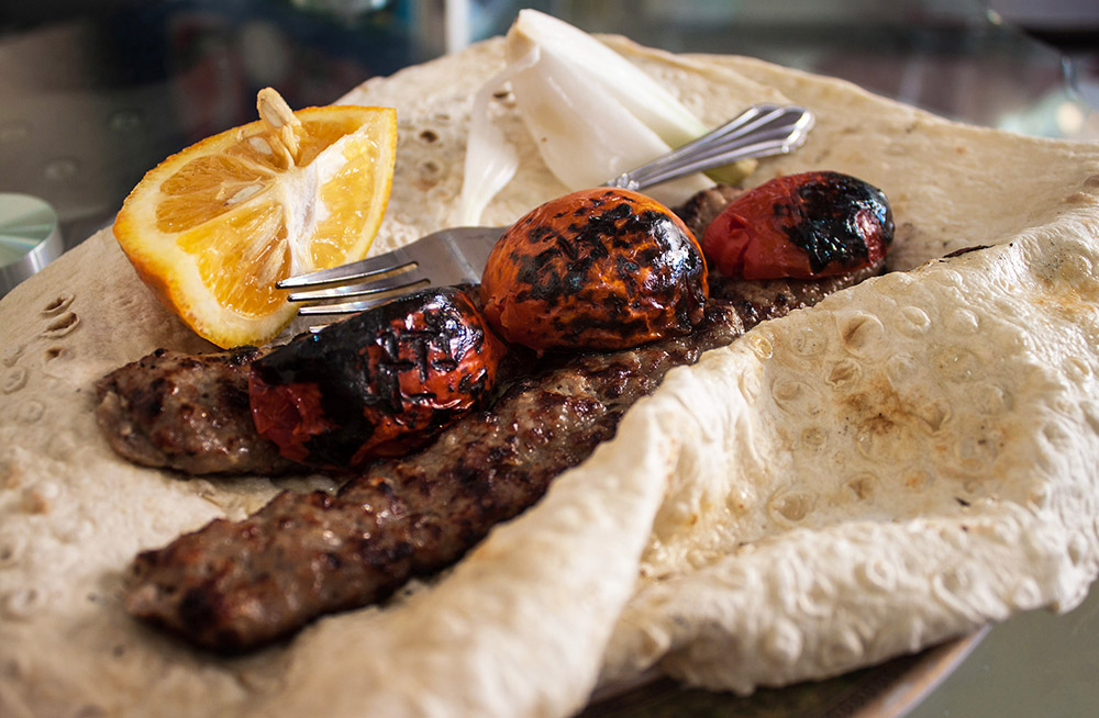 meat kebab on flatbread with roasted tomatoes