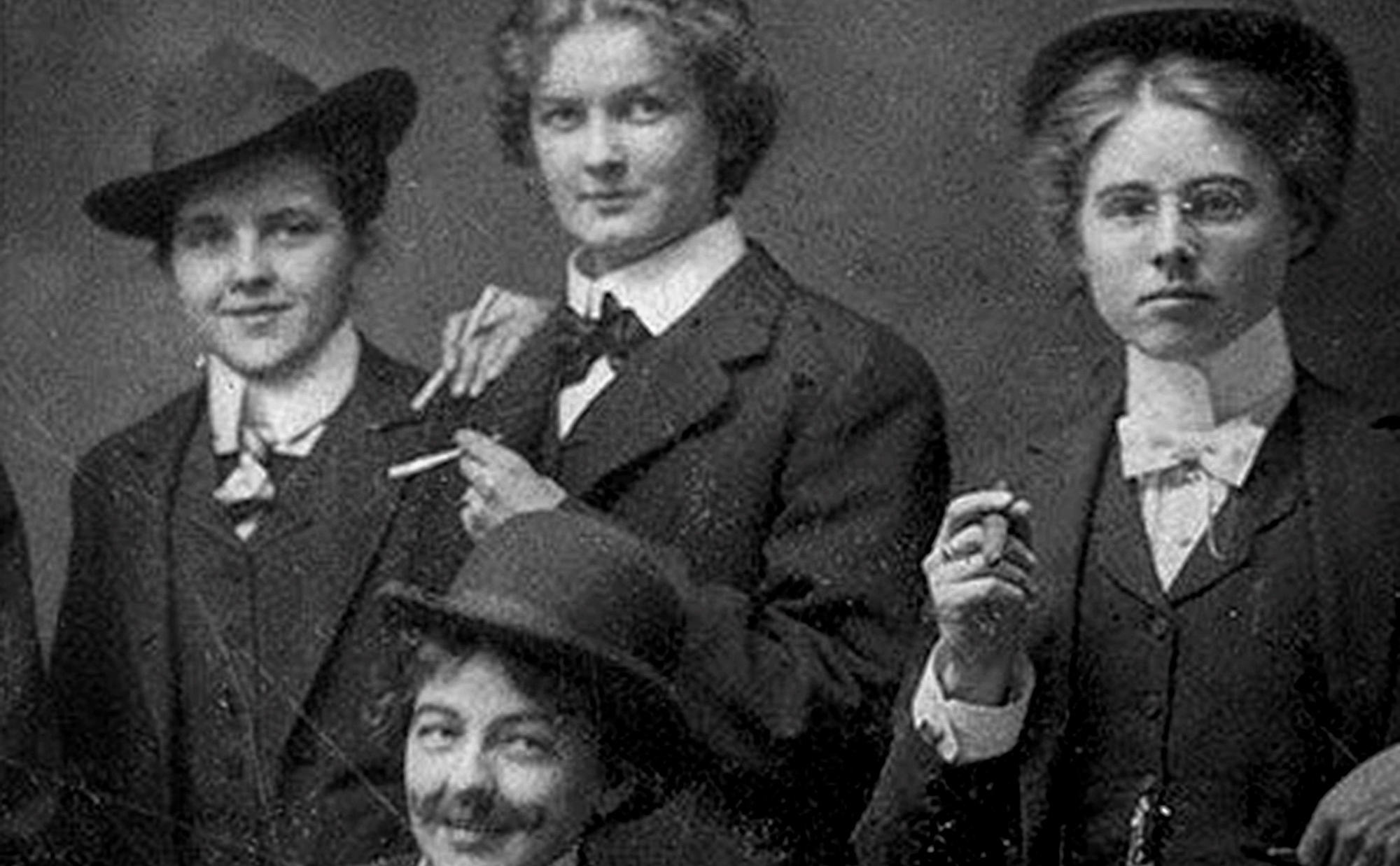 black and white photo of three 19th century women dressed as men in suits and ties