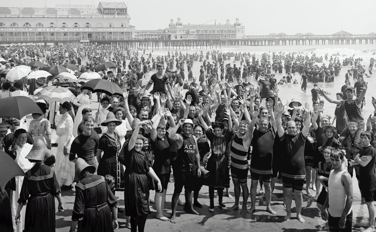 black and white photograph of hundreds of people standing on the beach in atlantic city, waving to the camera