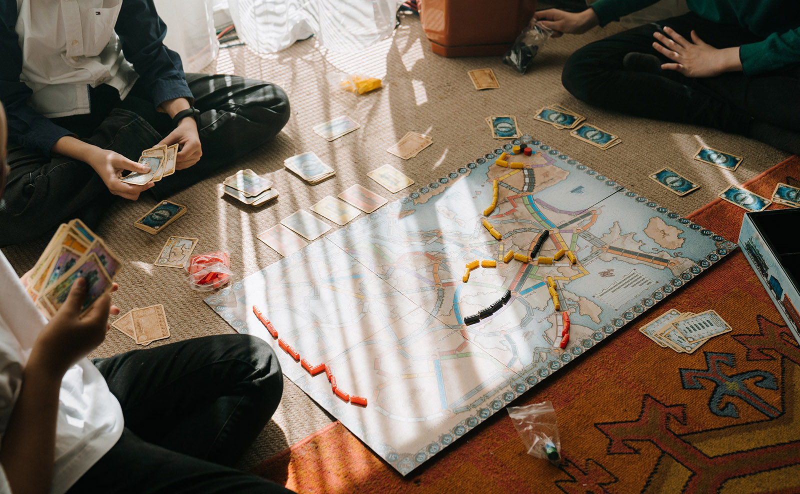 three people sitting on the floor playing a board game