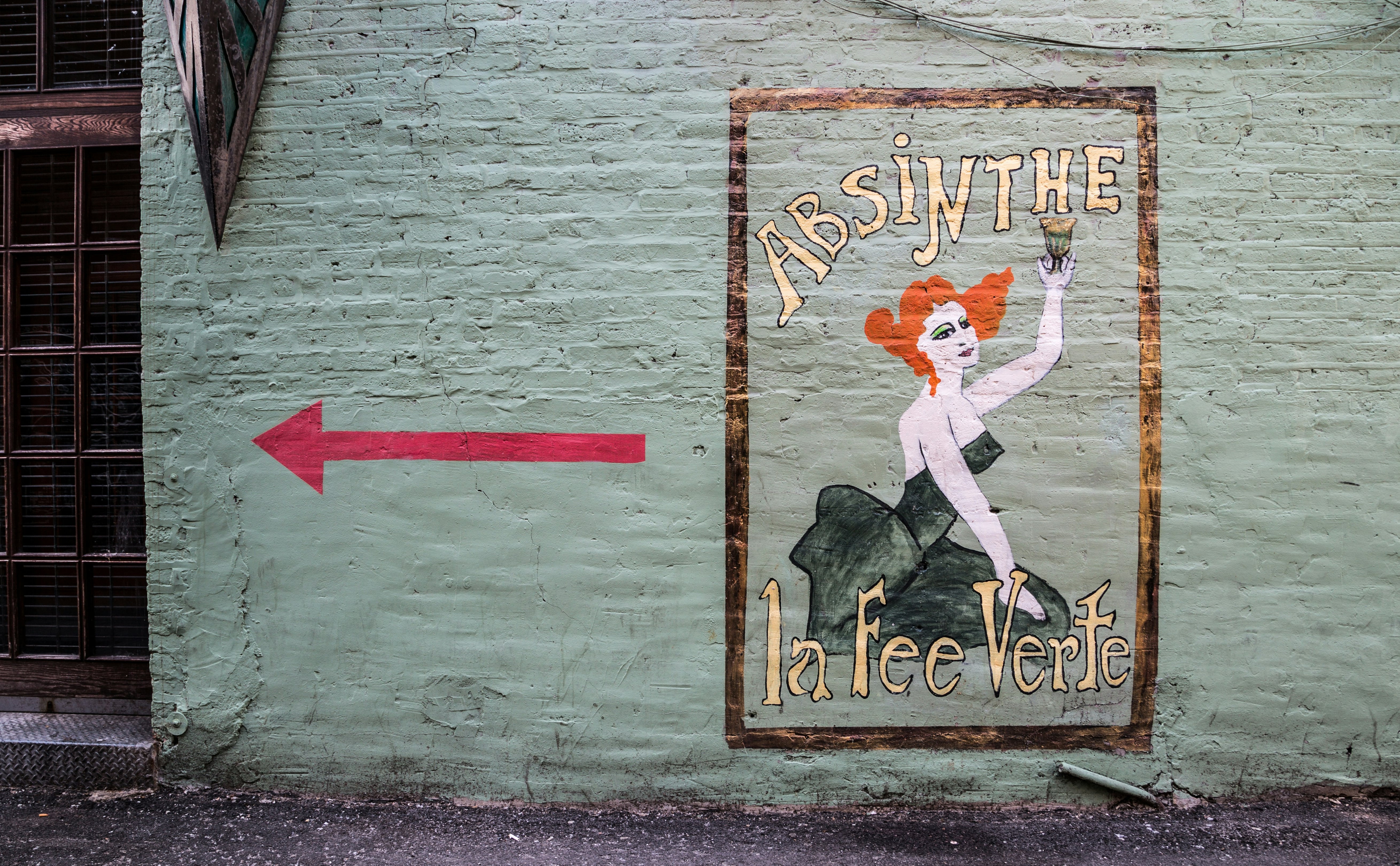 handpainted sign on a brick wall for absinthe with a mysterious looking woman