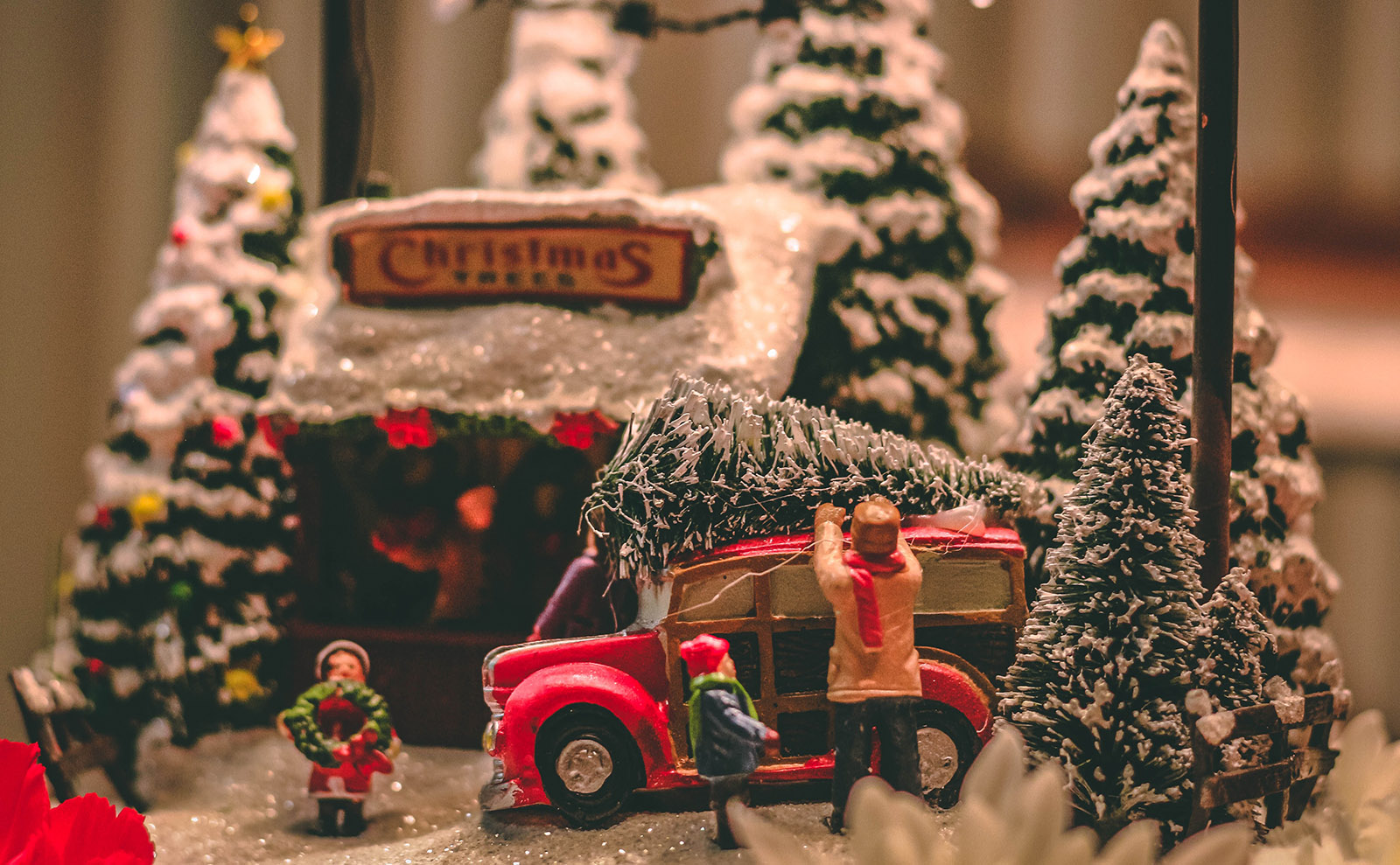 close up photo of a christmas scene made from toys of a family putting a christmas tree on top of their car