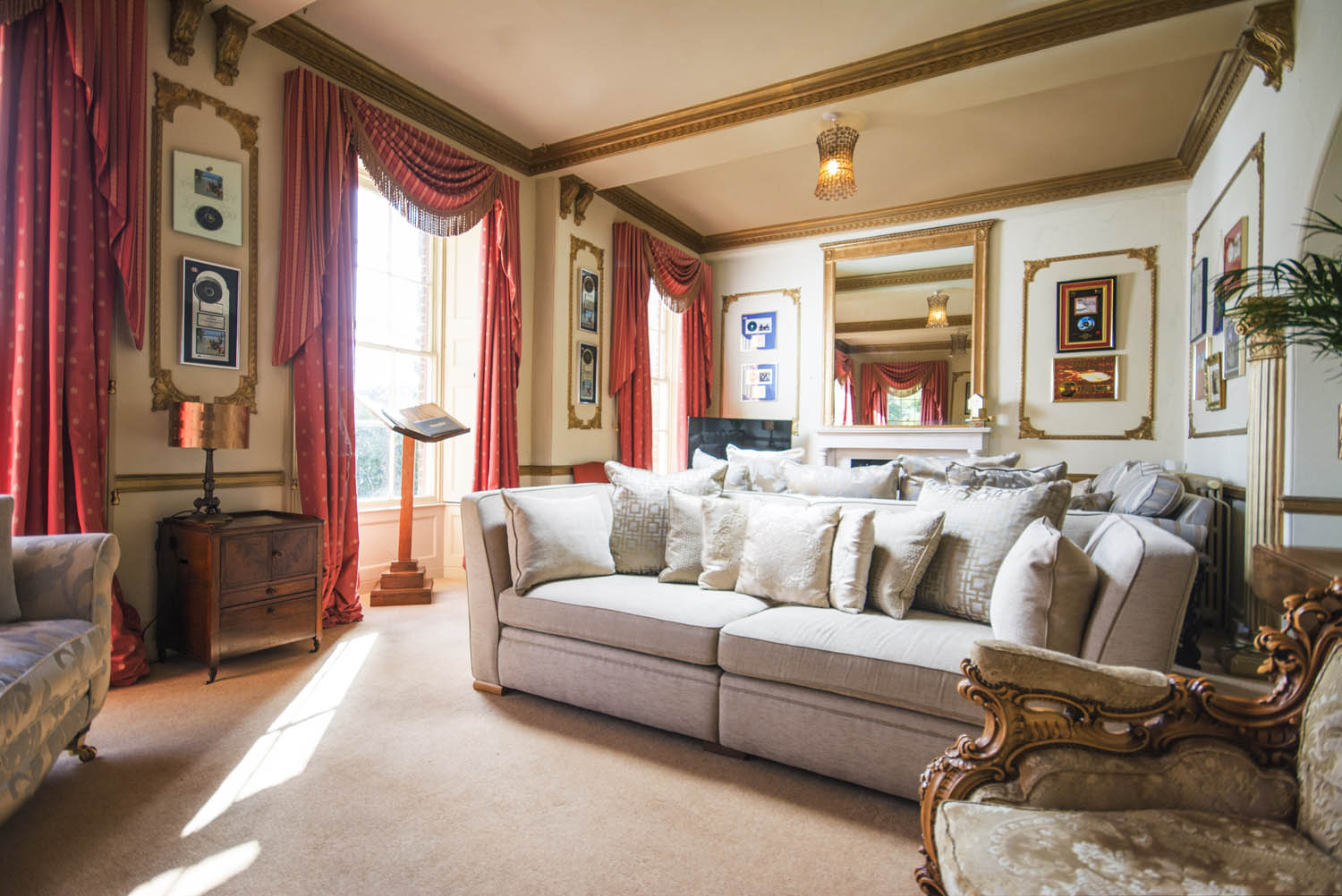 drawing room decorated with white fluffy couches and red drapes on the windows