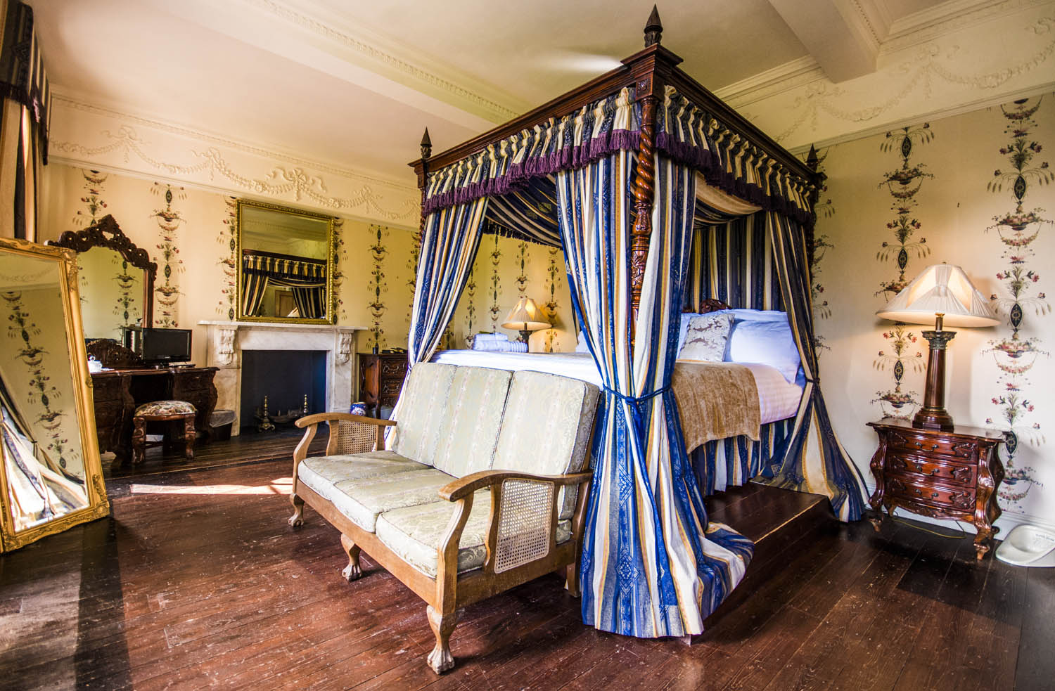 four poster bed with canopy in a bedroom with handpainted flowers on the wall