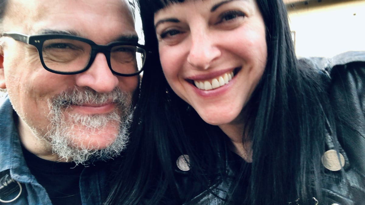 photograph of man wearing glasses with a woman with a blunt black fringe