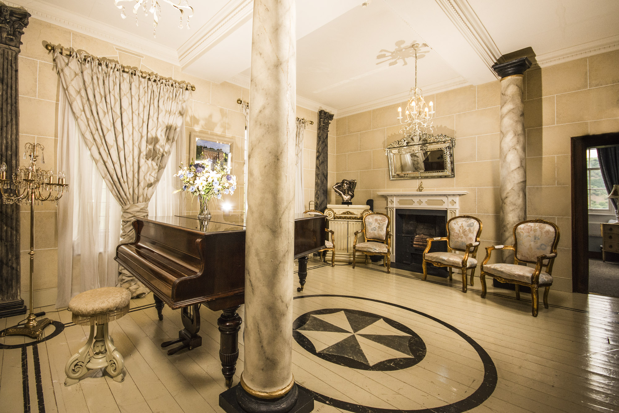 white room with a handpainted floor and grand piano