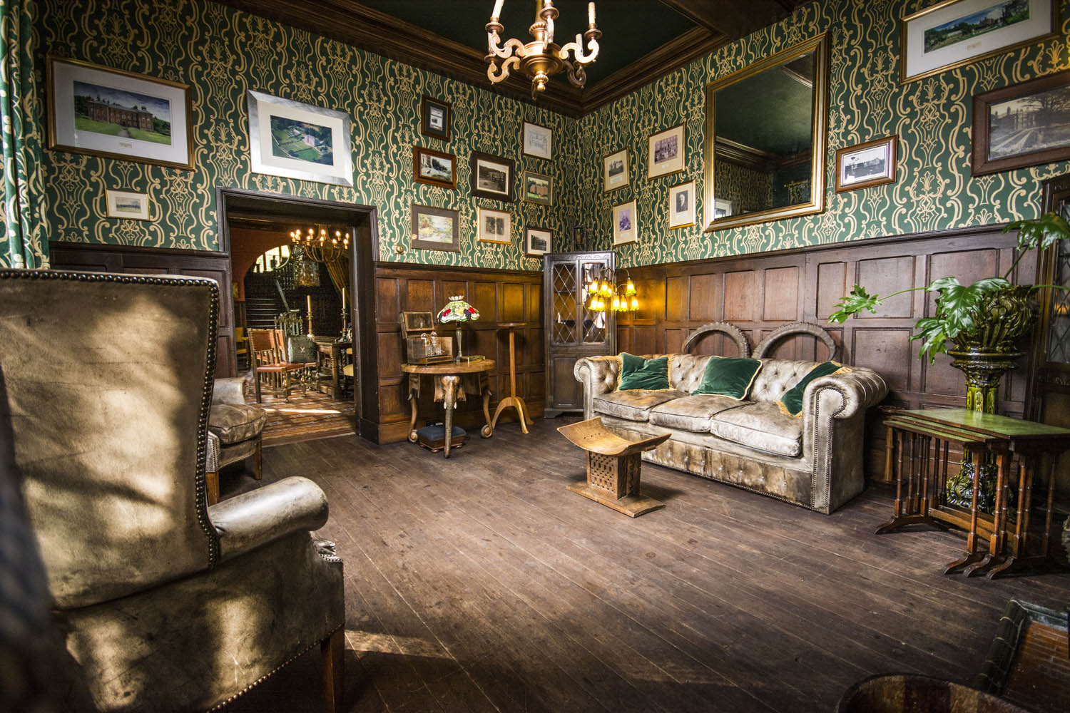 victorian room with wooden floor and green wallpaper and couch