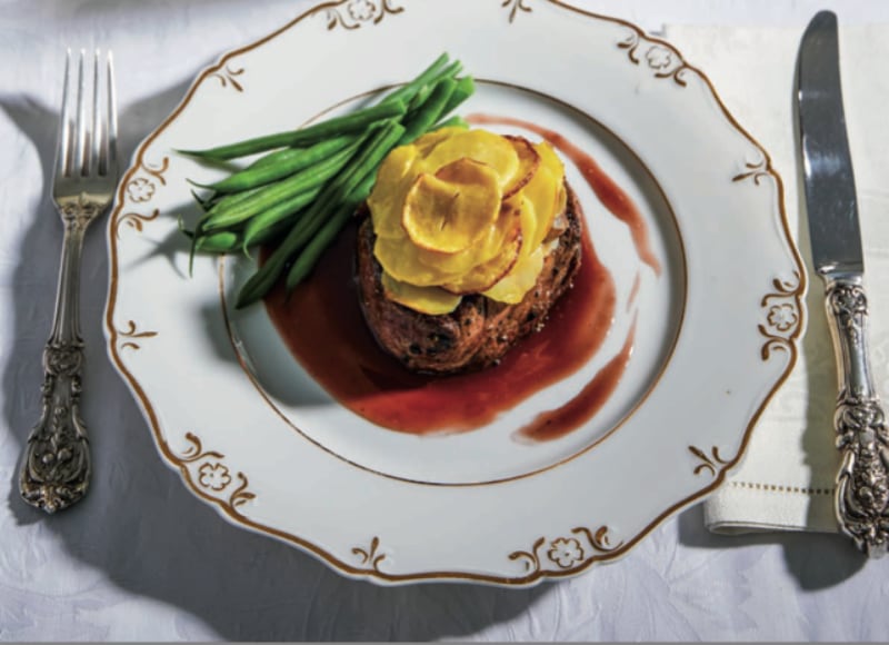 overhead photo of a steak and green beans on a white china plate