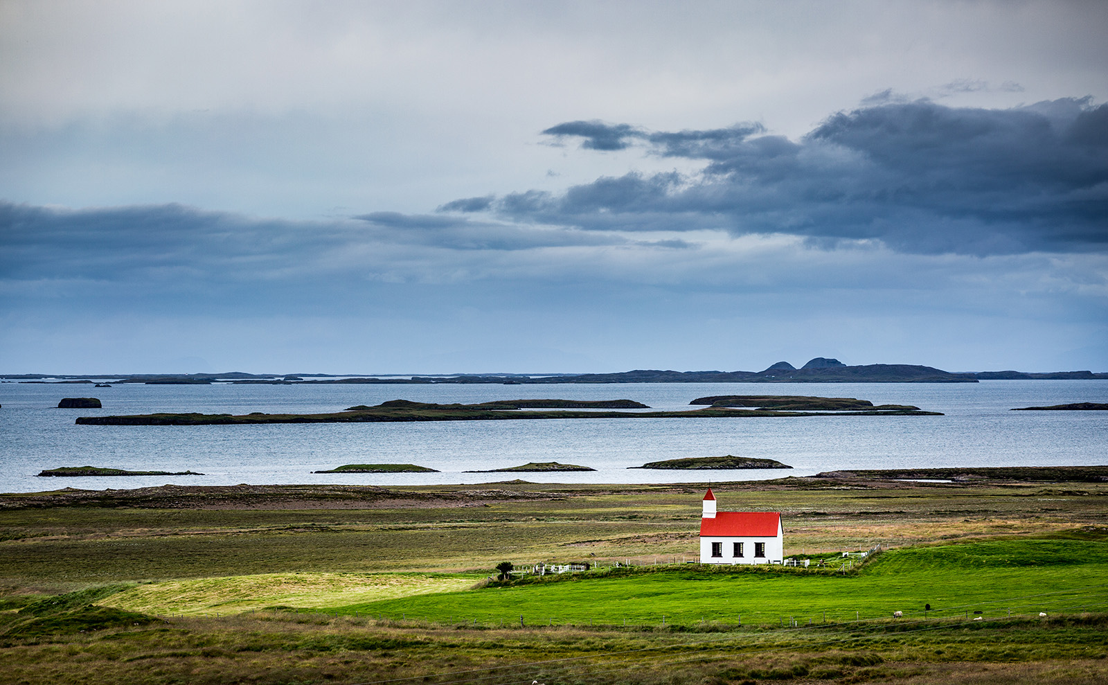 small red and white church sitting in the middle of a barren marsh