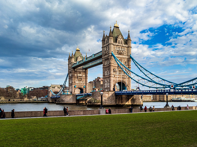 tower bridge in london taken from the bank of the river with a grassy lawn