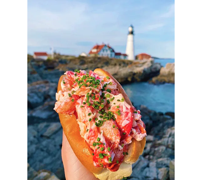 lobster roll sandwich with a white lighthouse in the background