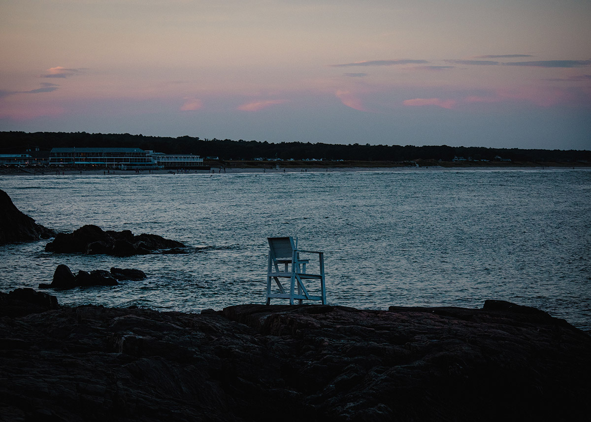 white beach chair sitting on a vacant beach at dusk