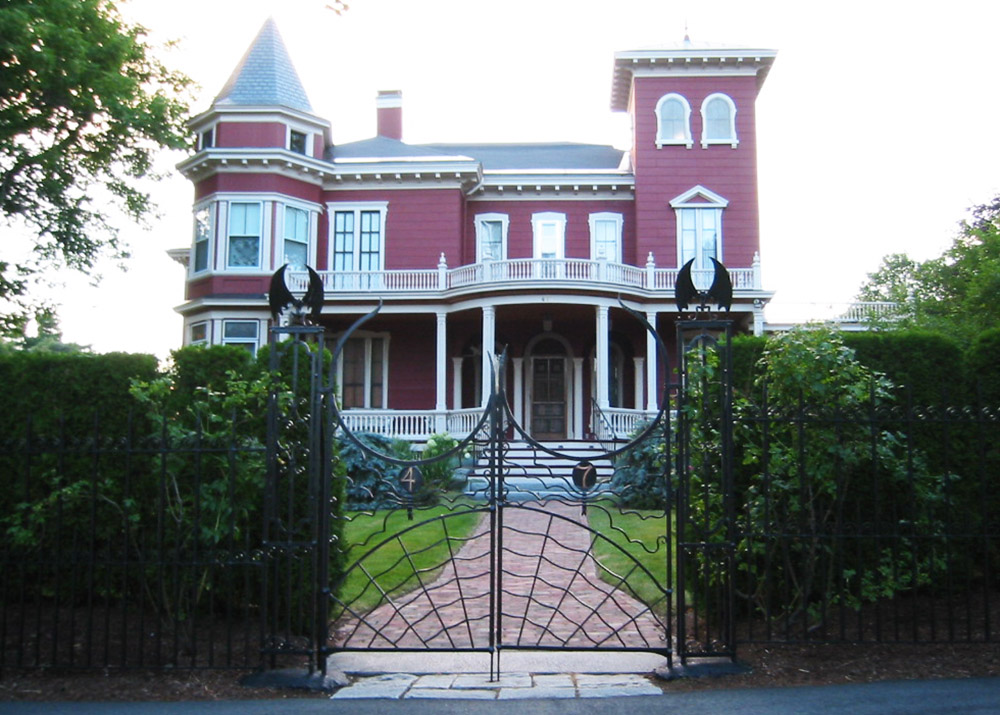 victorian red brick house in the background with a black wrought-iron gate in the foreground