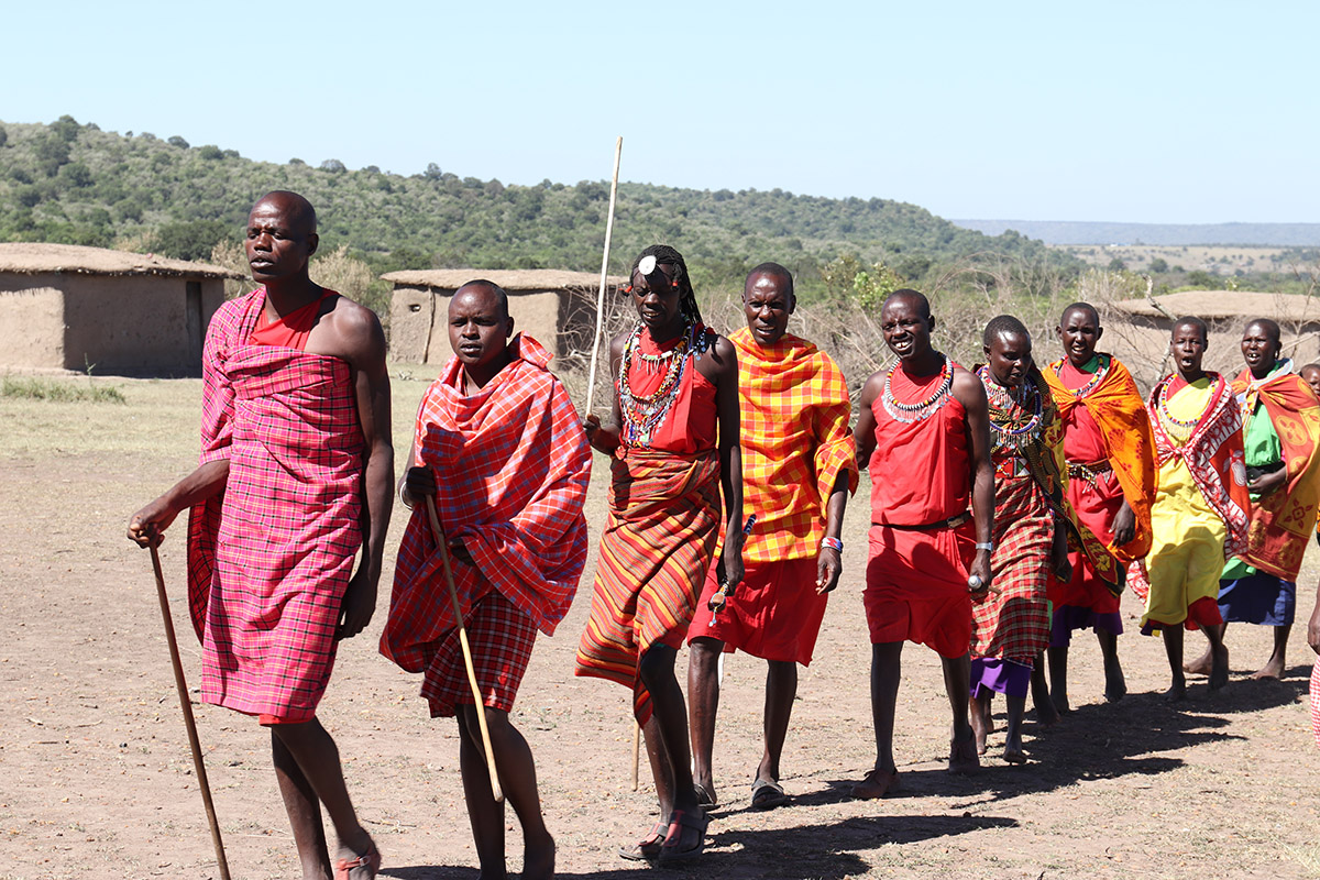  a line of maasai people wearing red fabric wraps