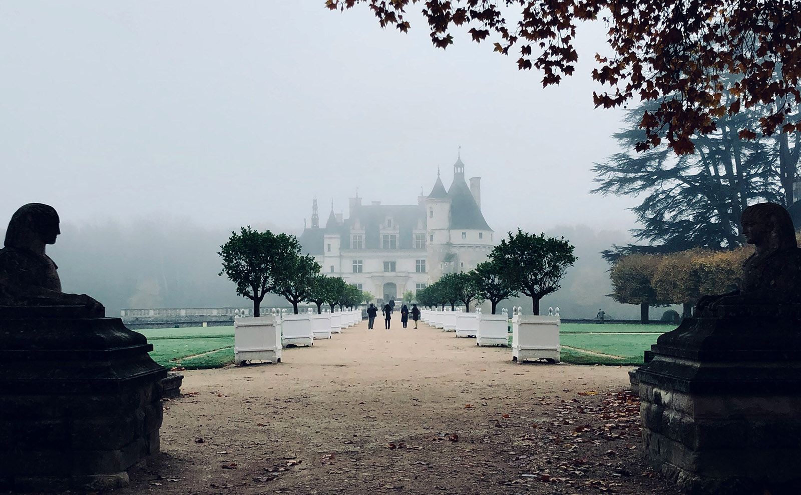 a white french chateau surrounded by mist and trees