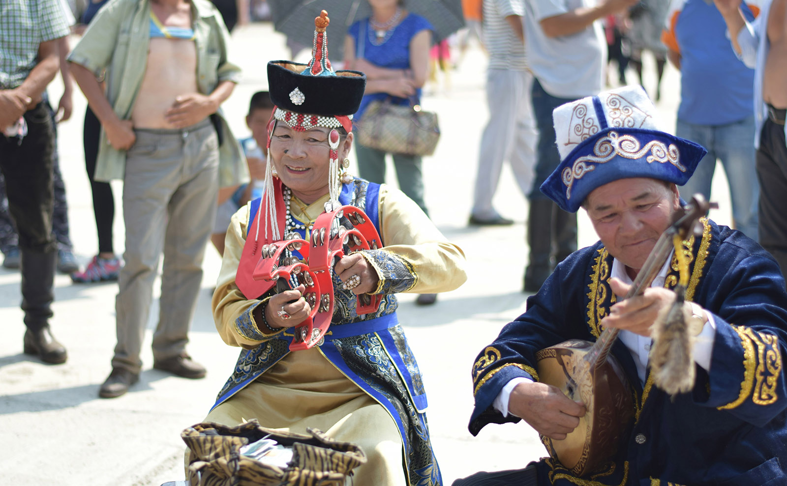 an elderly man and woman in traditional blue and red costumes playing musical instruments