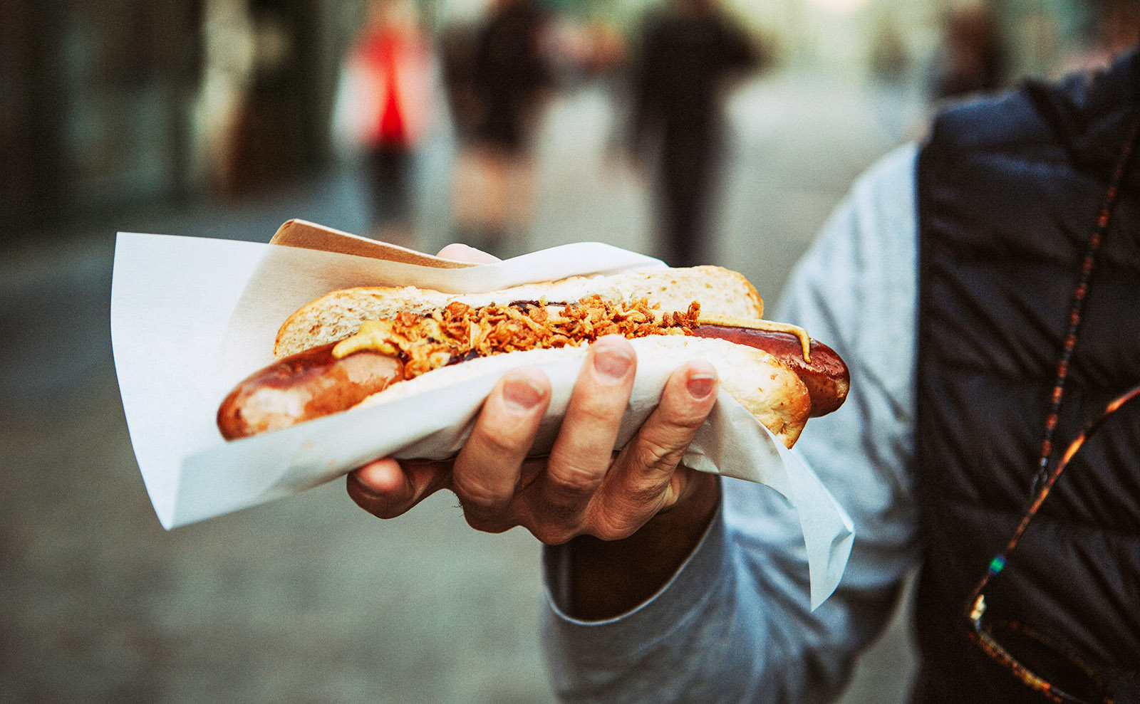 a large hot dog in a bun being held in someone's hand