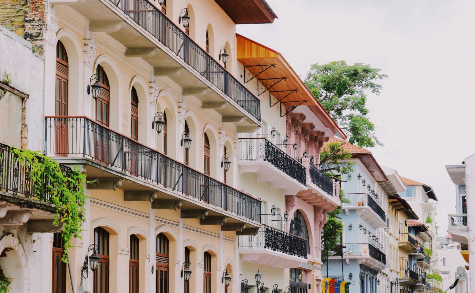 pastel colored colonial buildings with black wrought iron railings against a blue sky