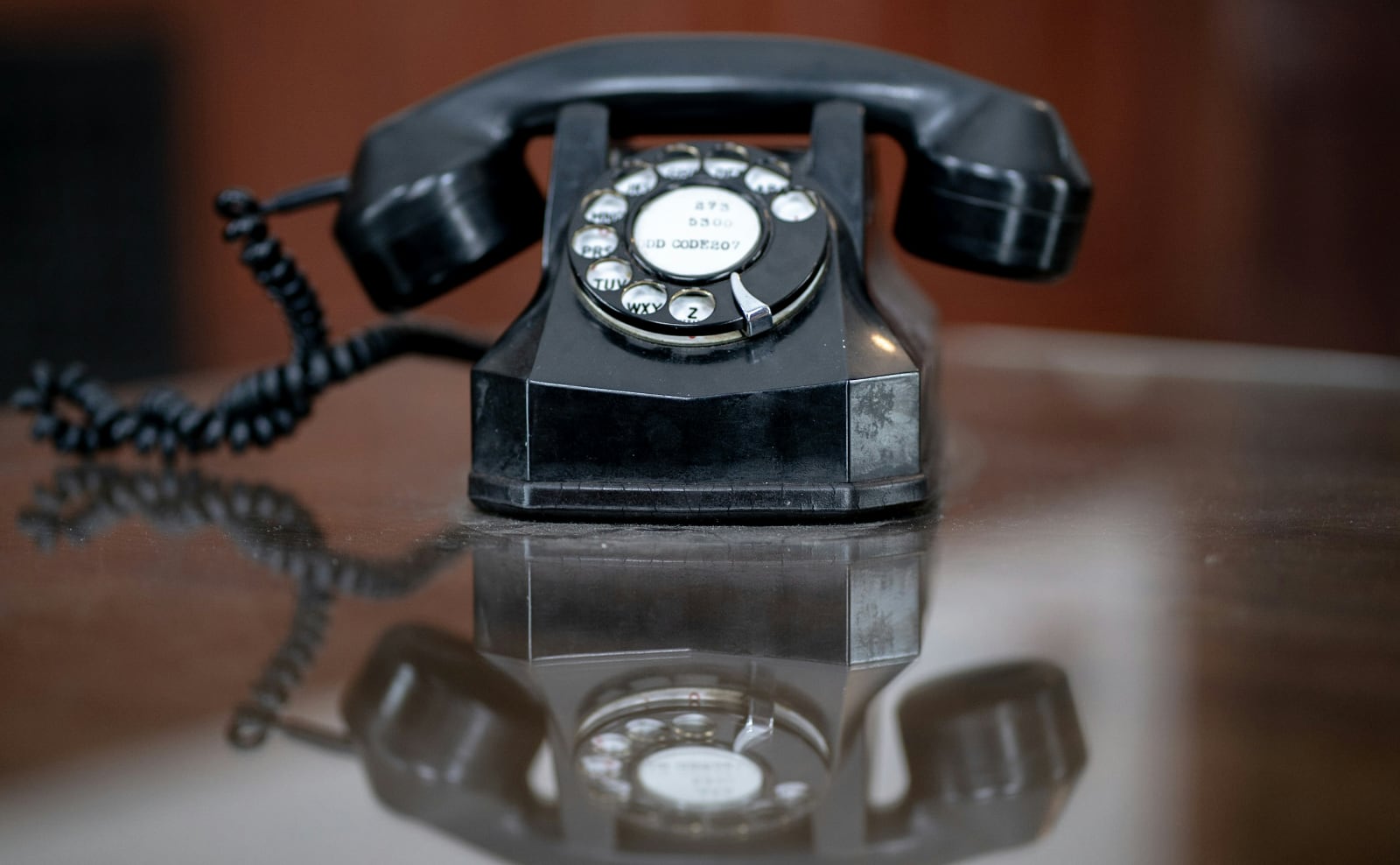 color photo of a retro black rotary telephone sitting on a desk