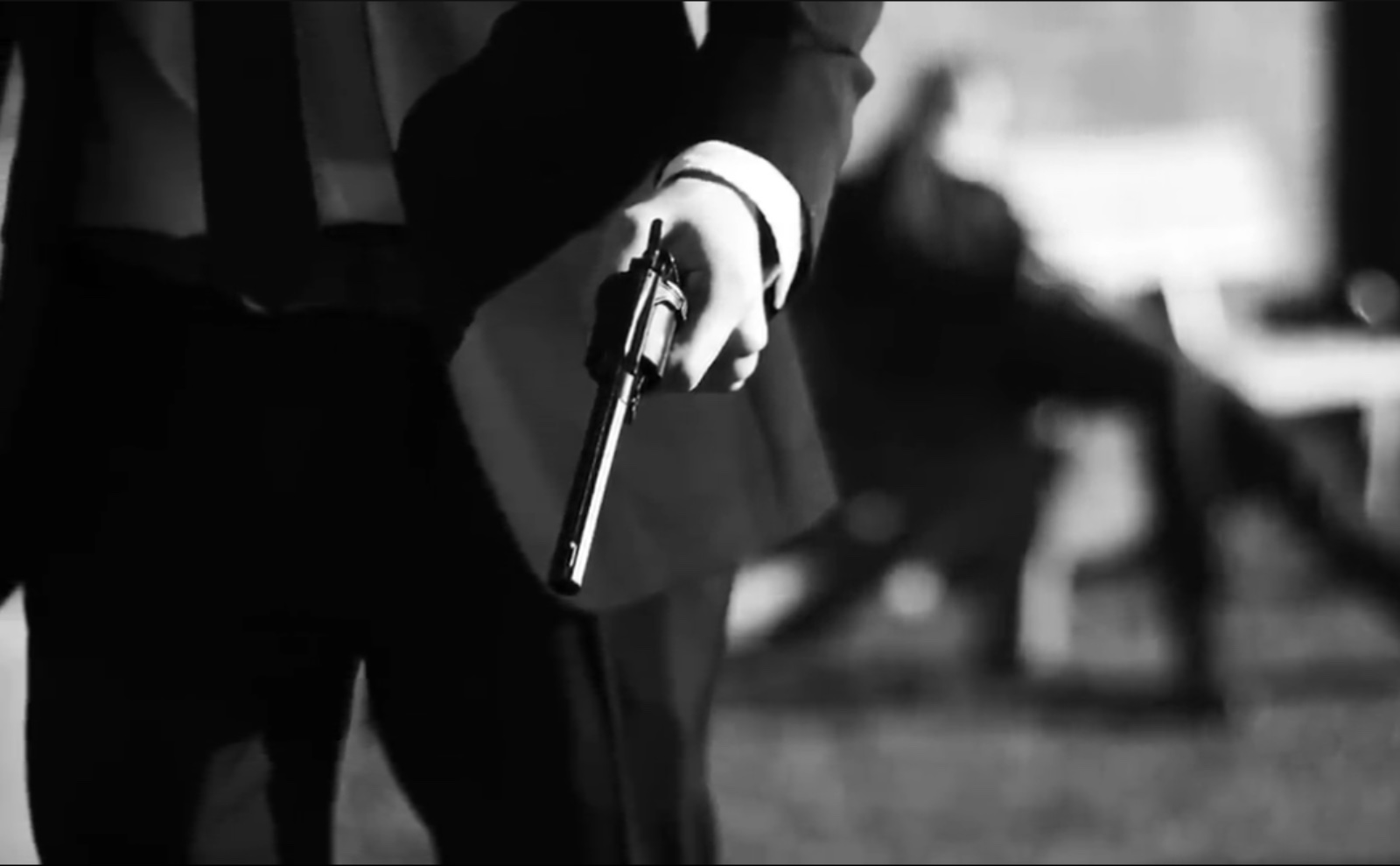 black and white photo of a close up of a man in a suit holding a pistol