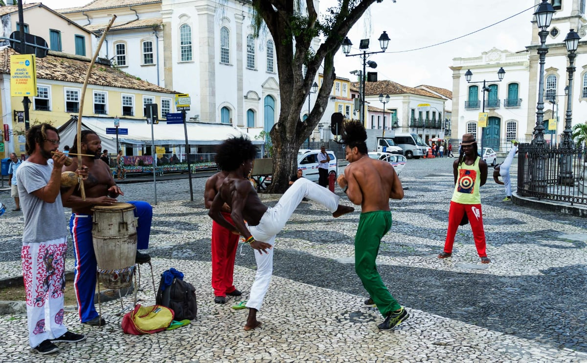 a group of men dancing and kicking as they practice capoeira in the street