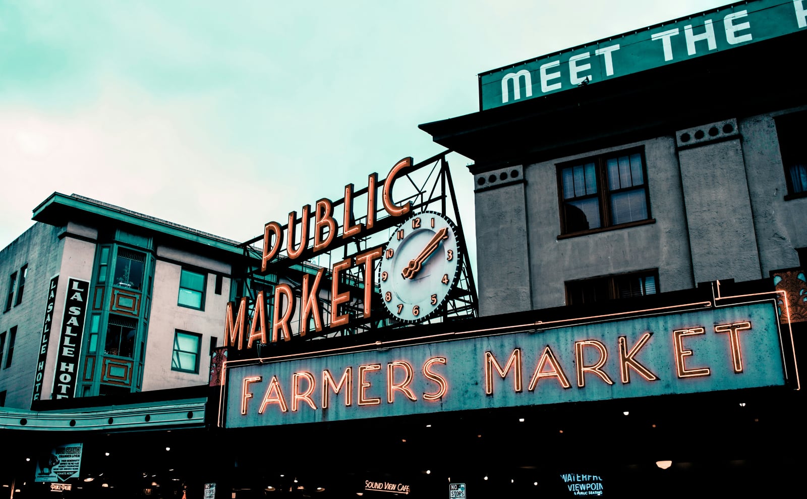 neon sign that says pike place market outside the market building in seattle