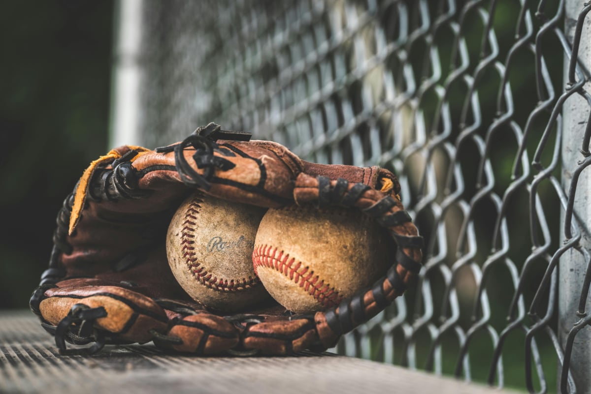 two dirty beatup baseballs sitting inside a well-worn baseball glove