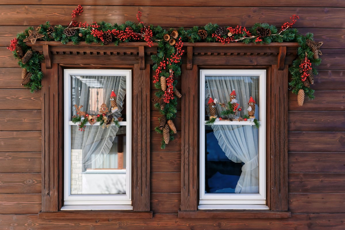 external view of windows decorated with green pine fronds and red berries