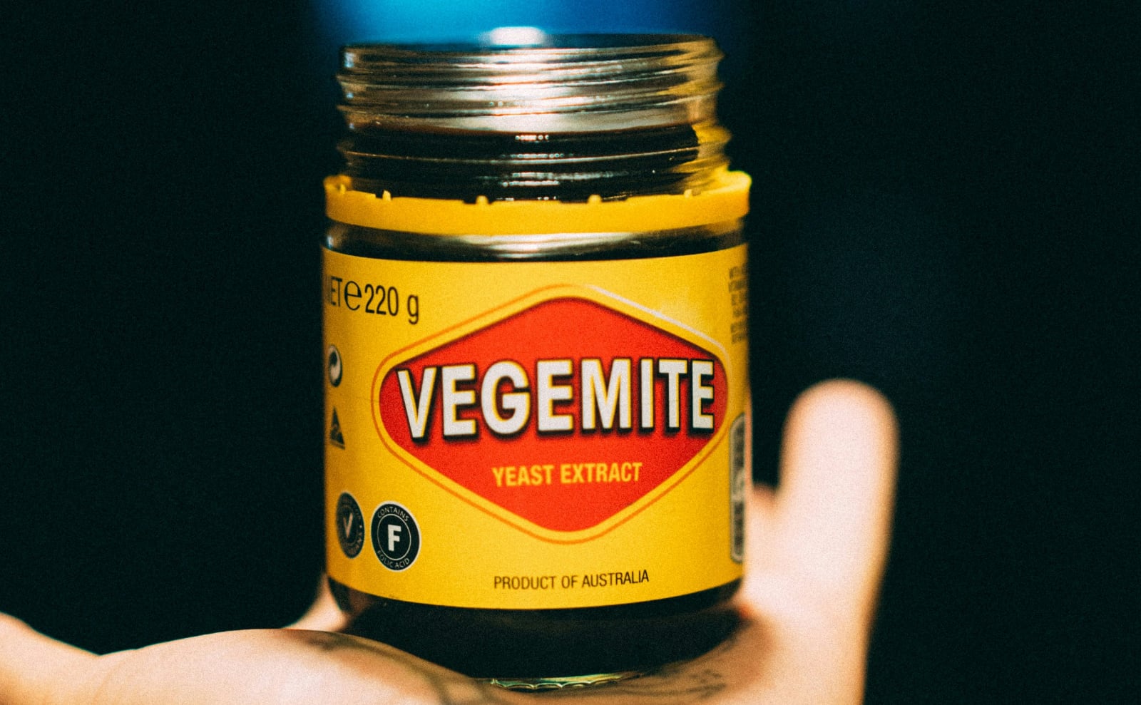 a jar of vegemite in a person's hand