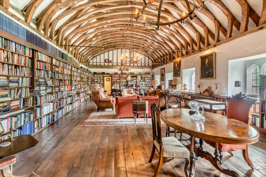 medieval library with bookshelves along the left wall and lots of light coming in the windows