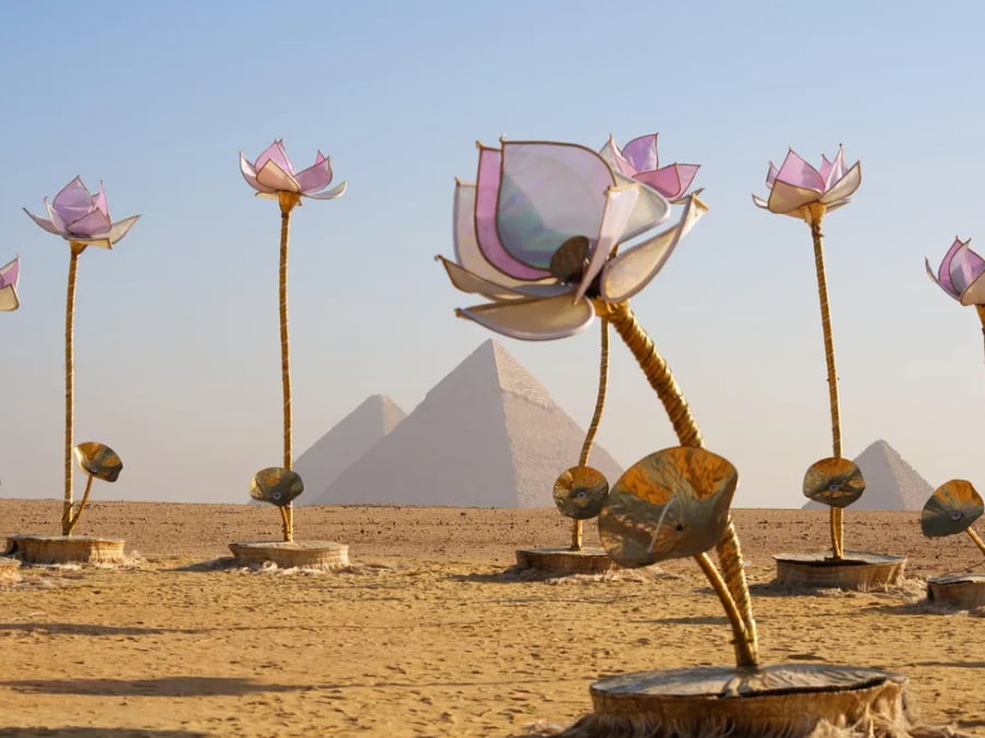 enormous delicate sculptures of lotus flowers in the desert with stone pyramids in the background