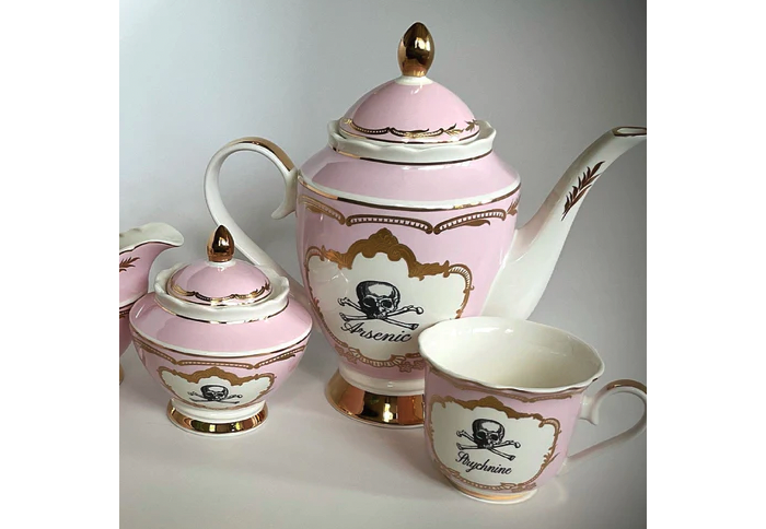  china tea set with two pink tea cups and a teapot decorated with a skull and crossbones and the word arsenic