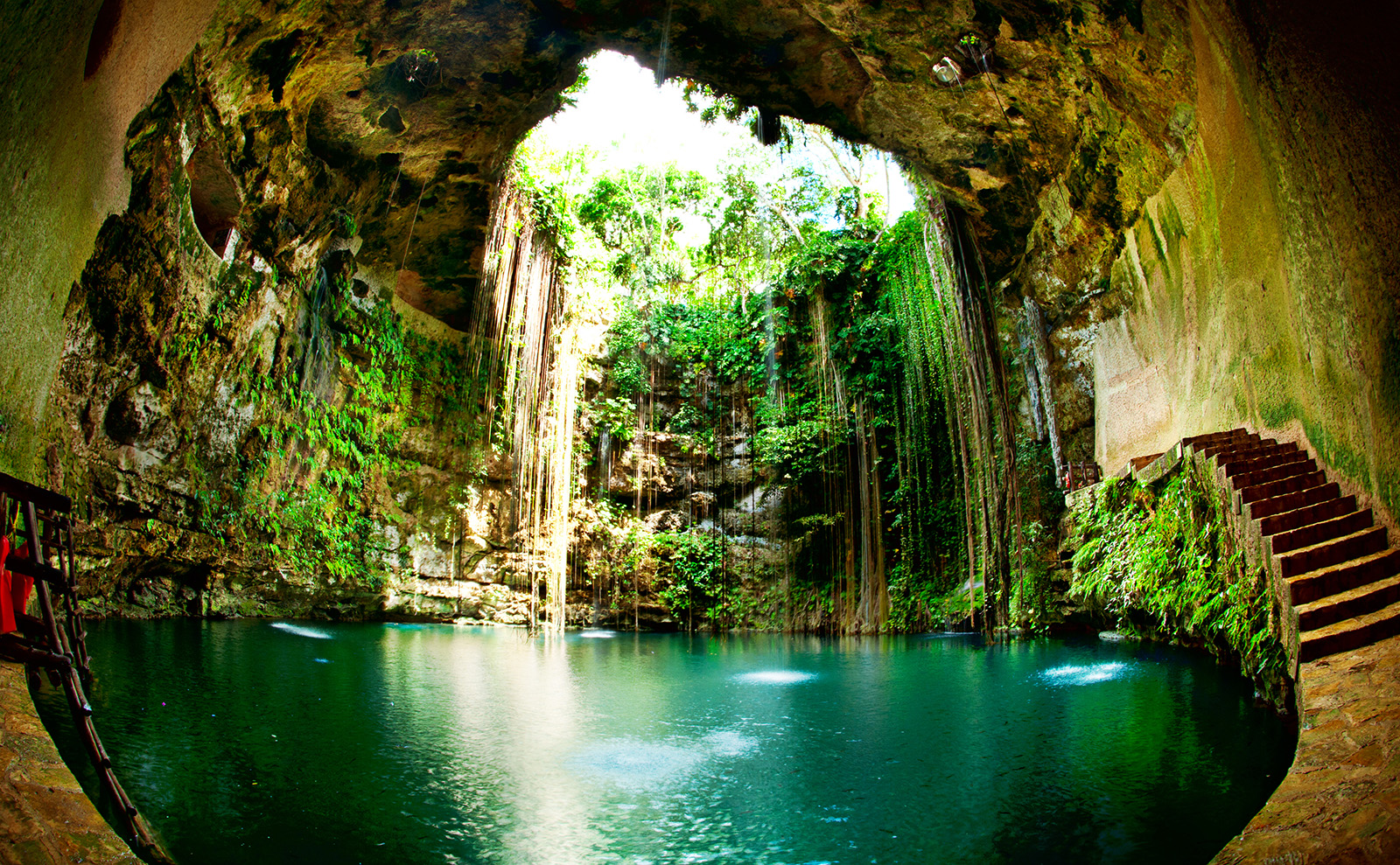 blue water in a cave with vines in Ik-Kil Cenote, Chichen Itza, Mexico