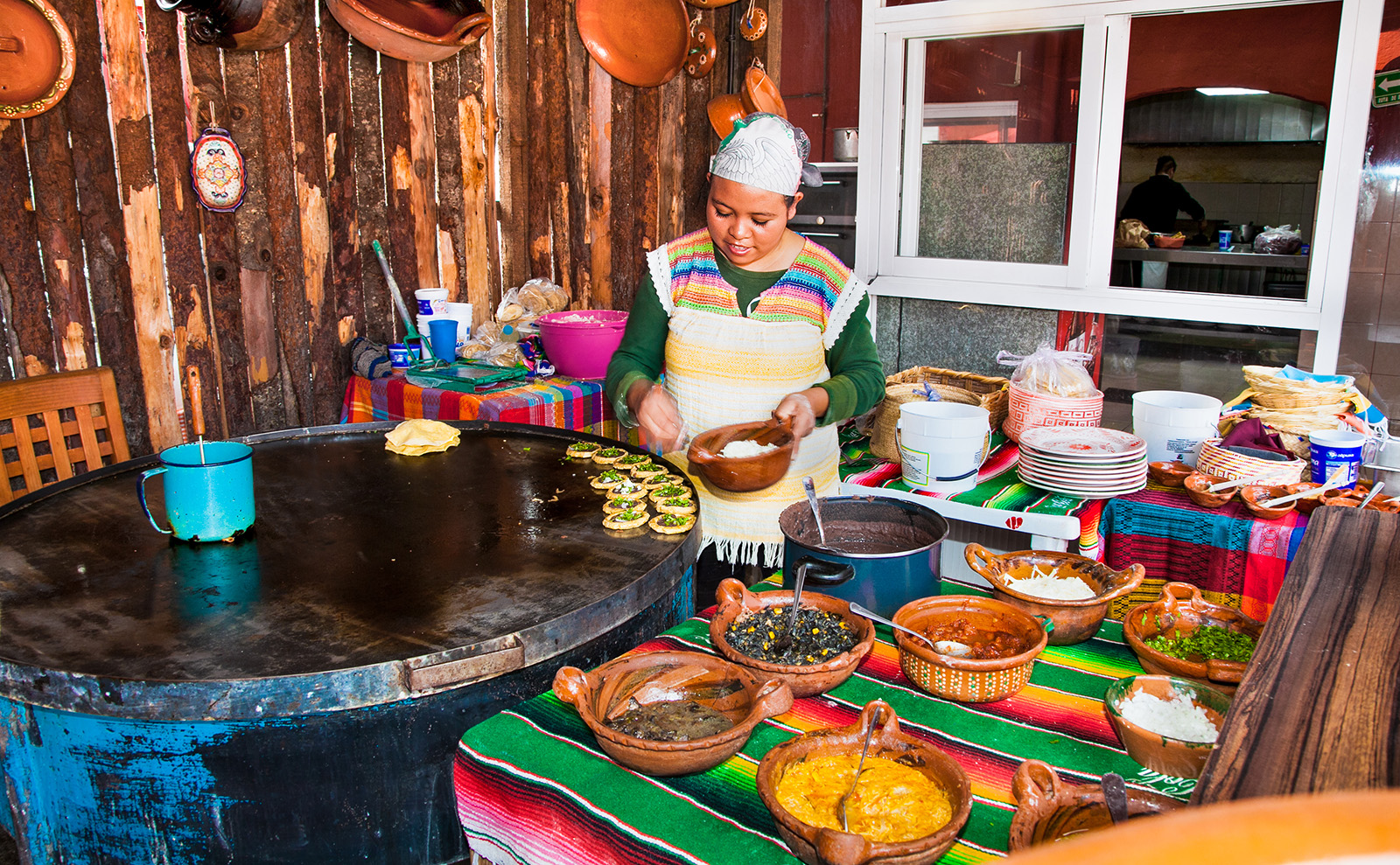 mexican girl cooking food surrounded by colorful bowls in Teotihuacan, Mexico