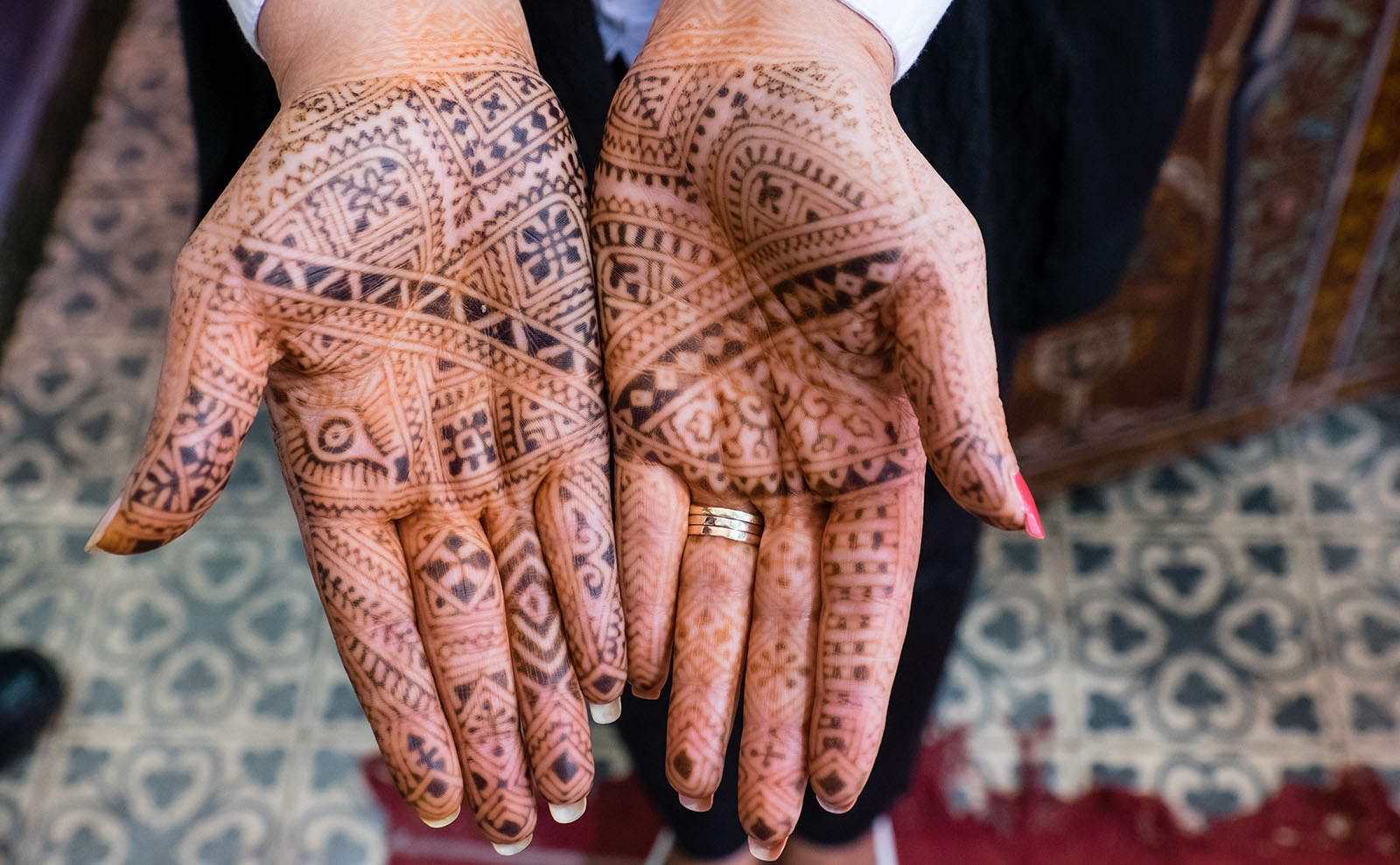 a woman's hands displaying dark henna tattoos