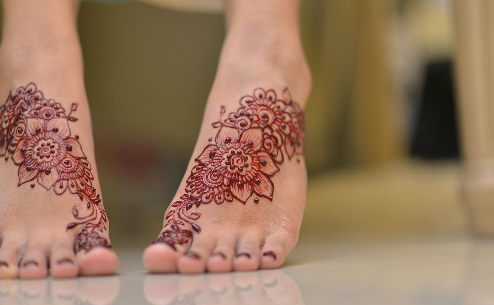 a woman's feet displaying black henna tattoos