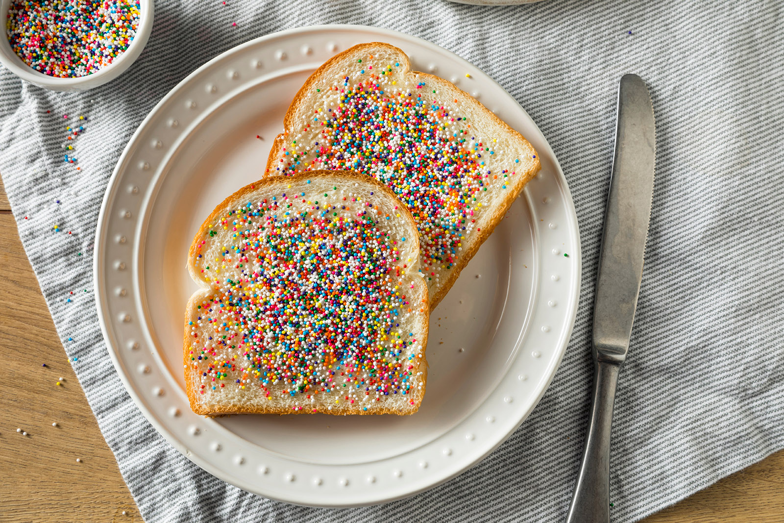 white bread with butter and multi-colored candy sprinkles on a cutting board