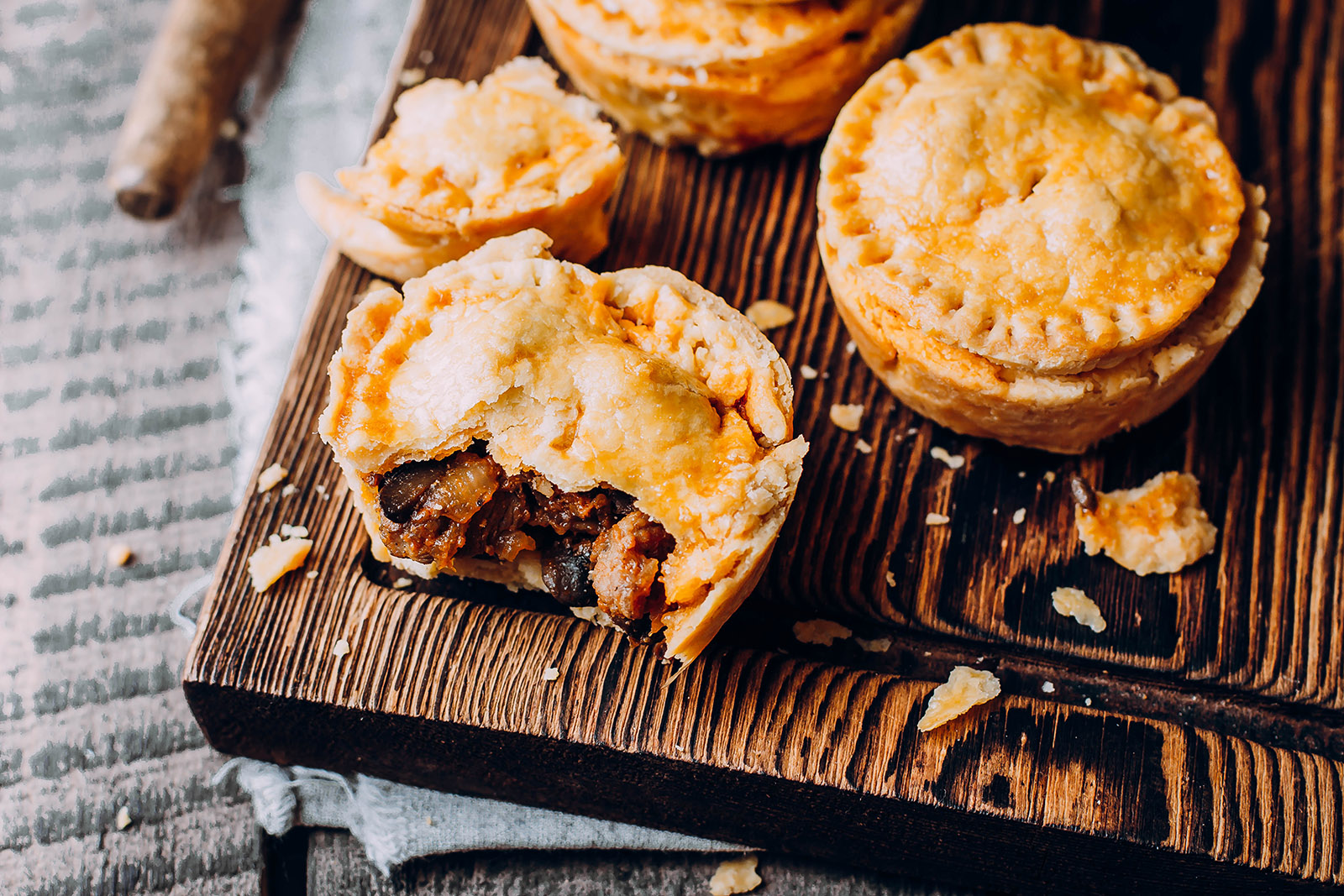 flaky meat pies displayed on a wooden cutting board