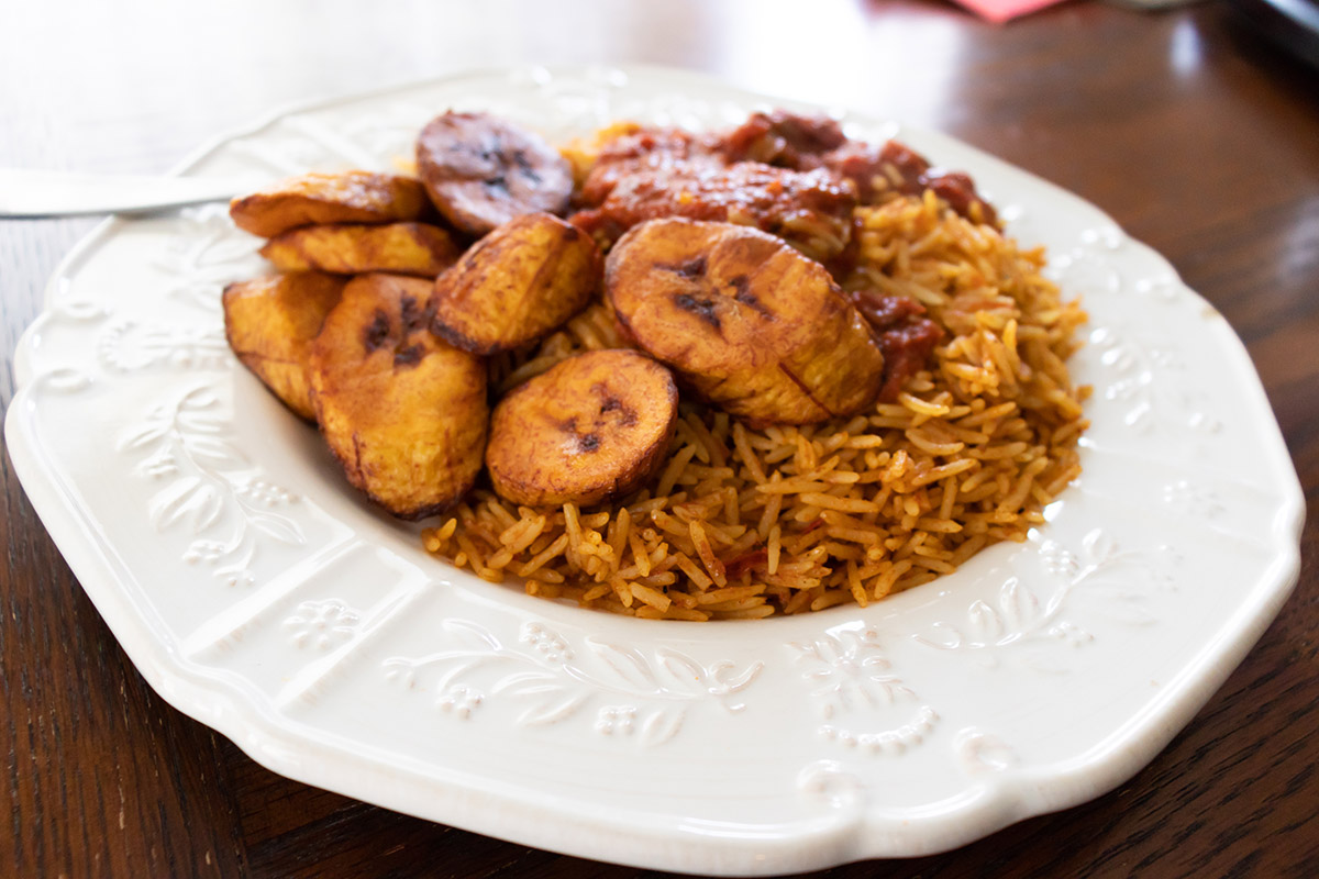 white bowl of jollof rice with fried plantains