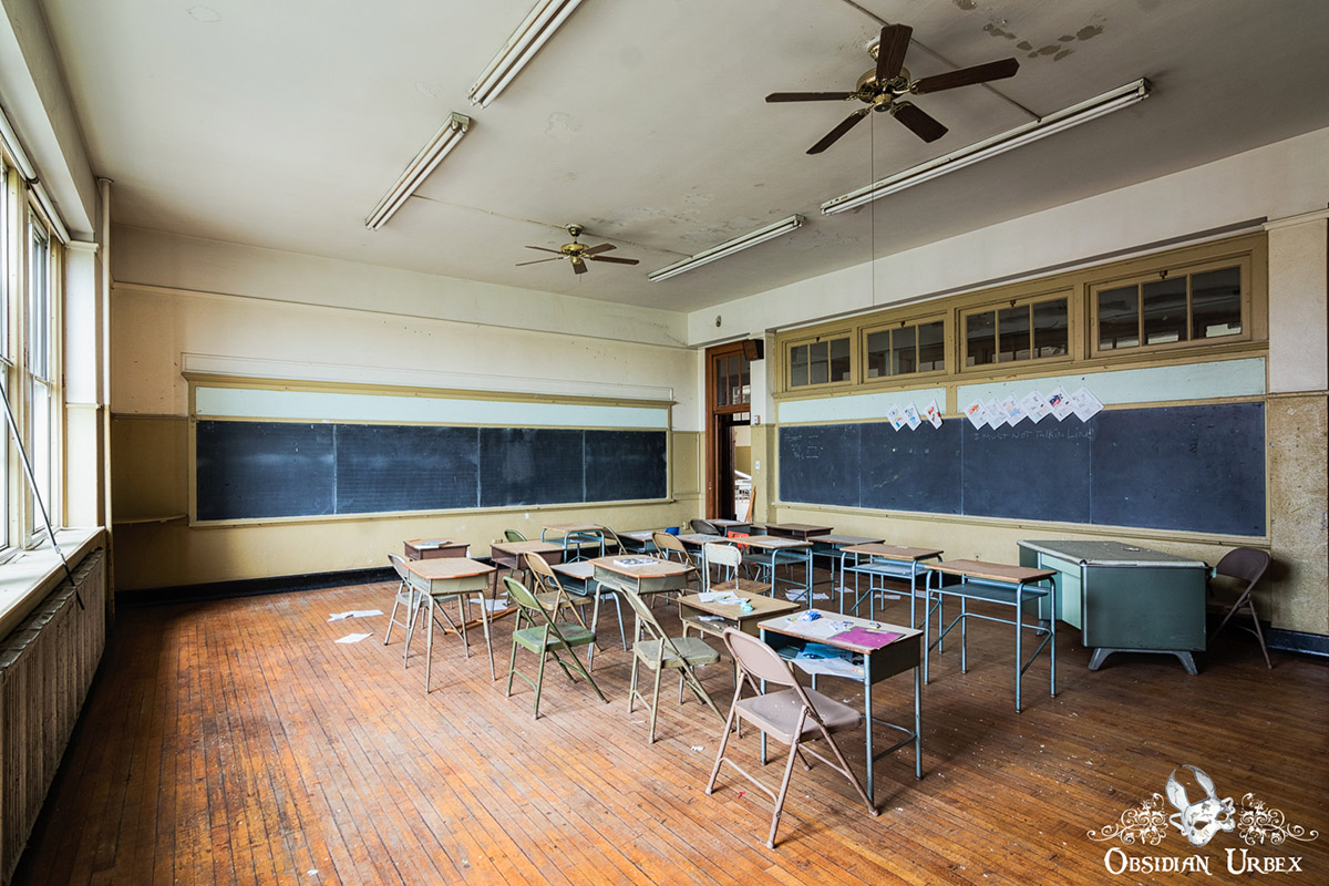 abandoned classroom with chalkboard and student desks