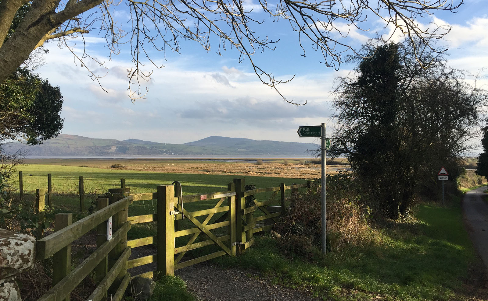 sun shining over a green field and a wooden gate