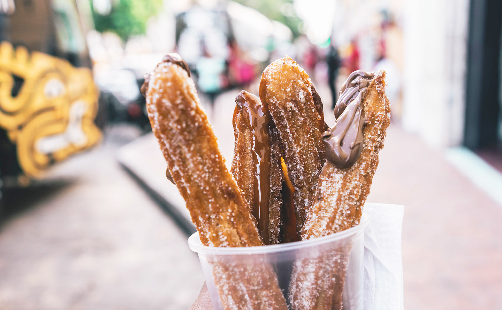 paper cone of churros with chocolate sauce
