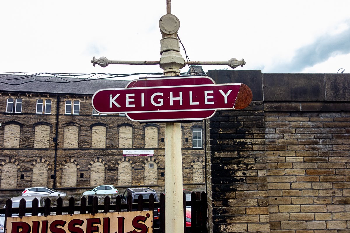 maroon sign with the word keighley at the keighley train station