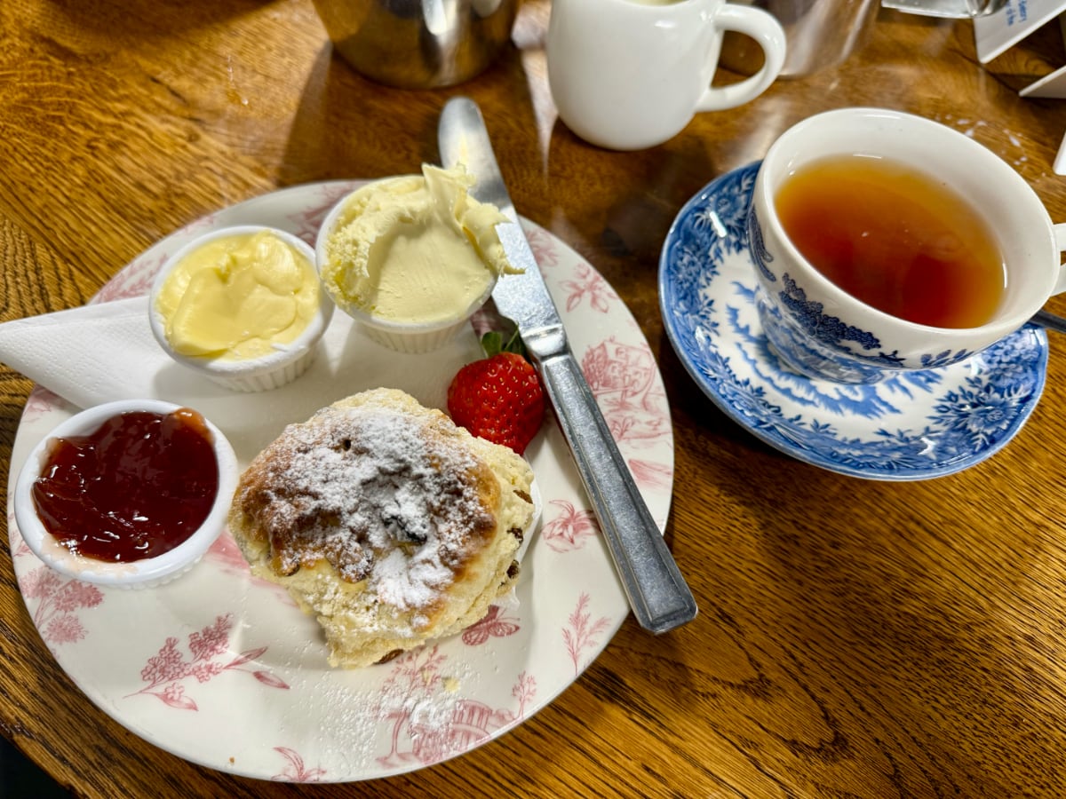 scone on a plate with a crock of jam and butter